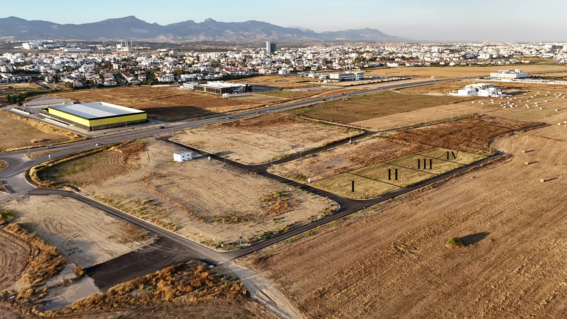 Aerial view of all four Lider commercial parcels, marked I to IV, at Metehan, Nicosia, with the city skyline and mountains behind