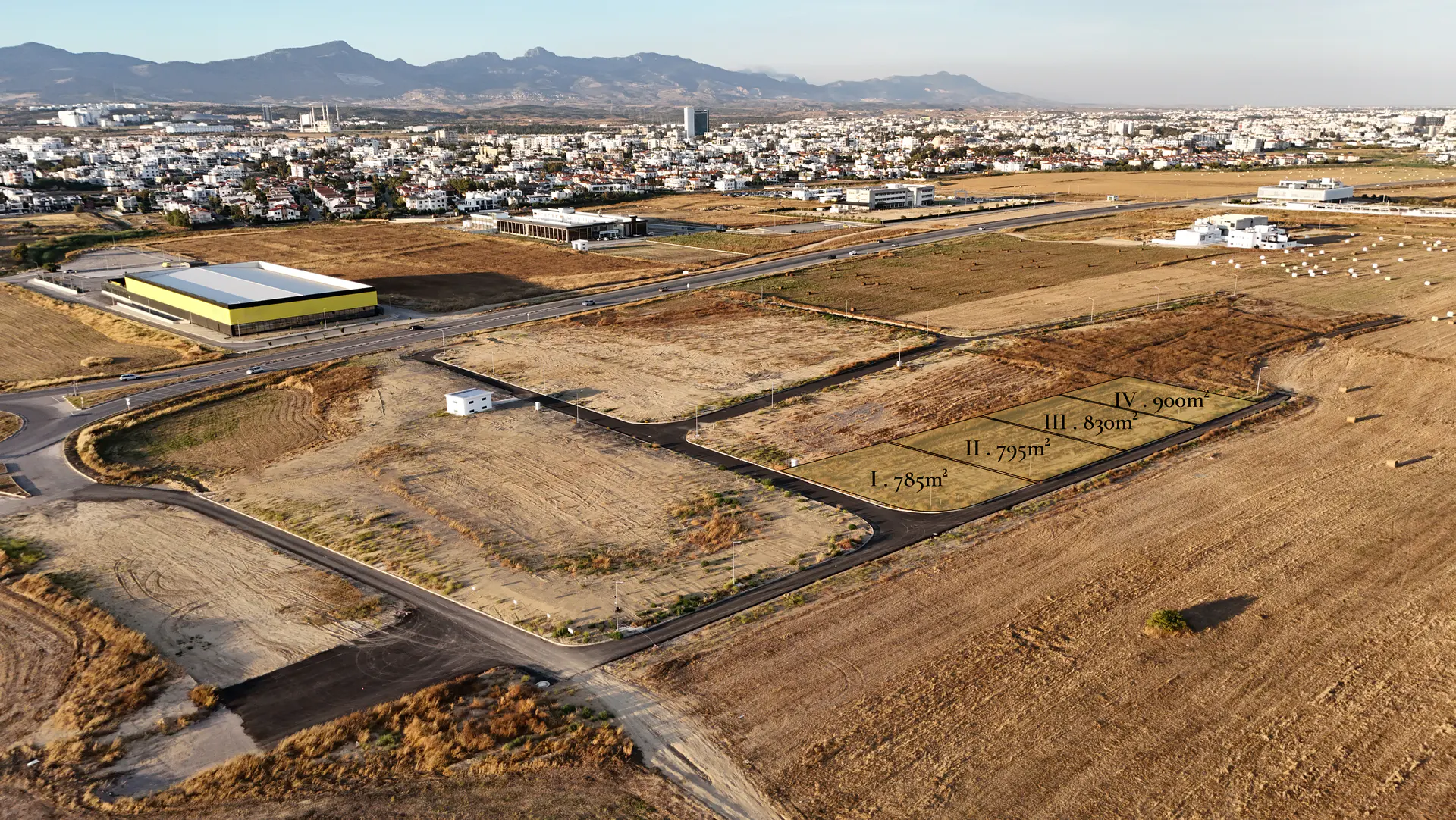 Aerial view of all four Lider commercial parcels together at Metehan, Nicosia (Parcel I 785m², II 795m², III 830m², IV 900m²), with the city skyline and mountains behind